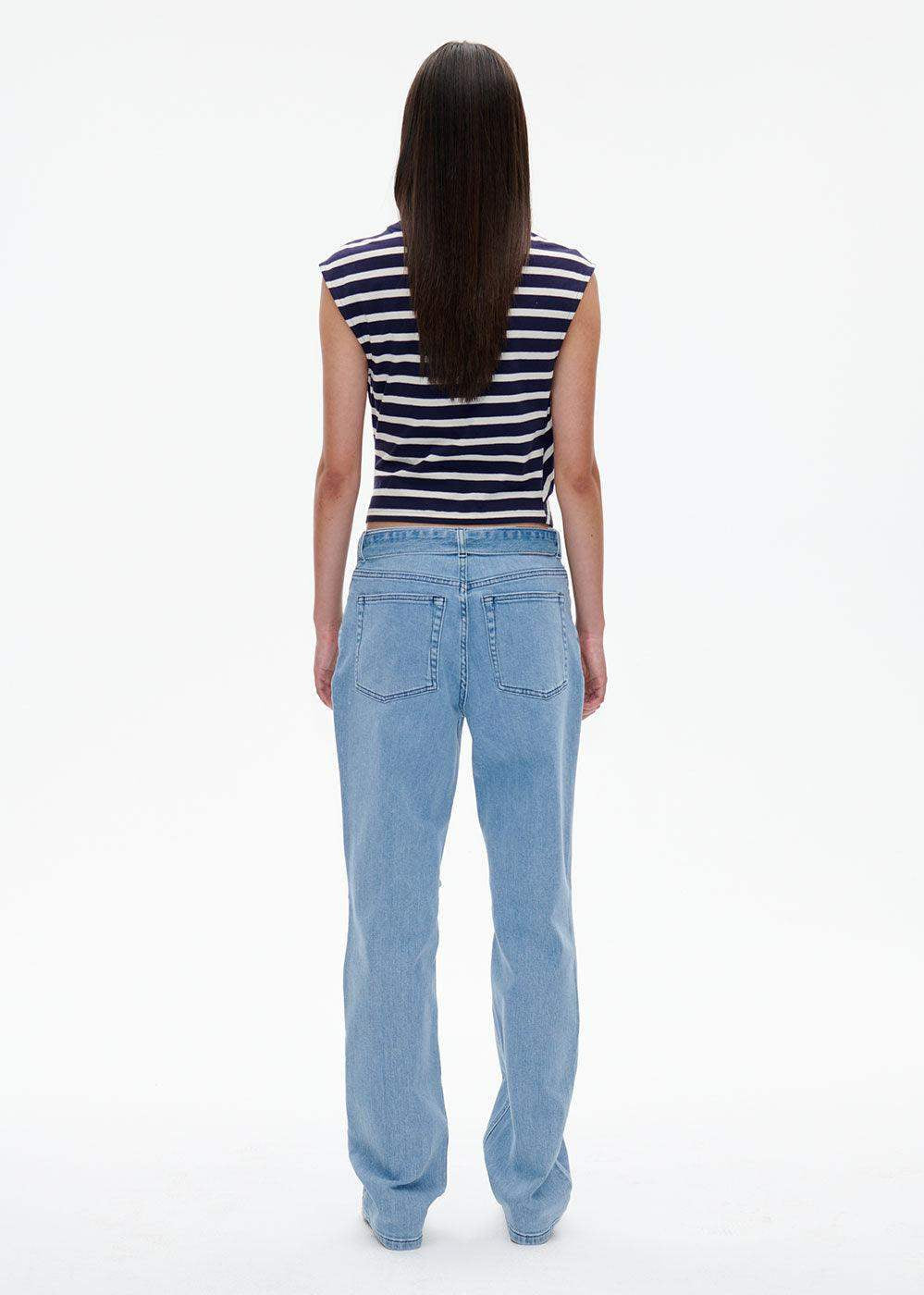 Woman in a navy striped sleeveless crop top and light blue straight-leg jeans, rear view
