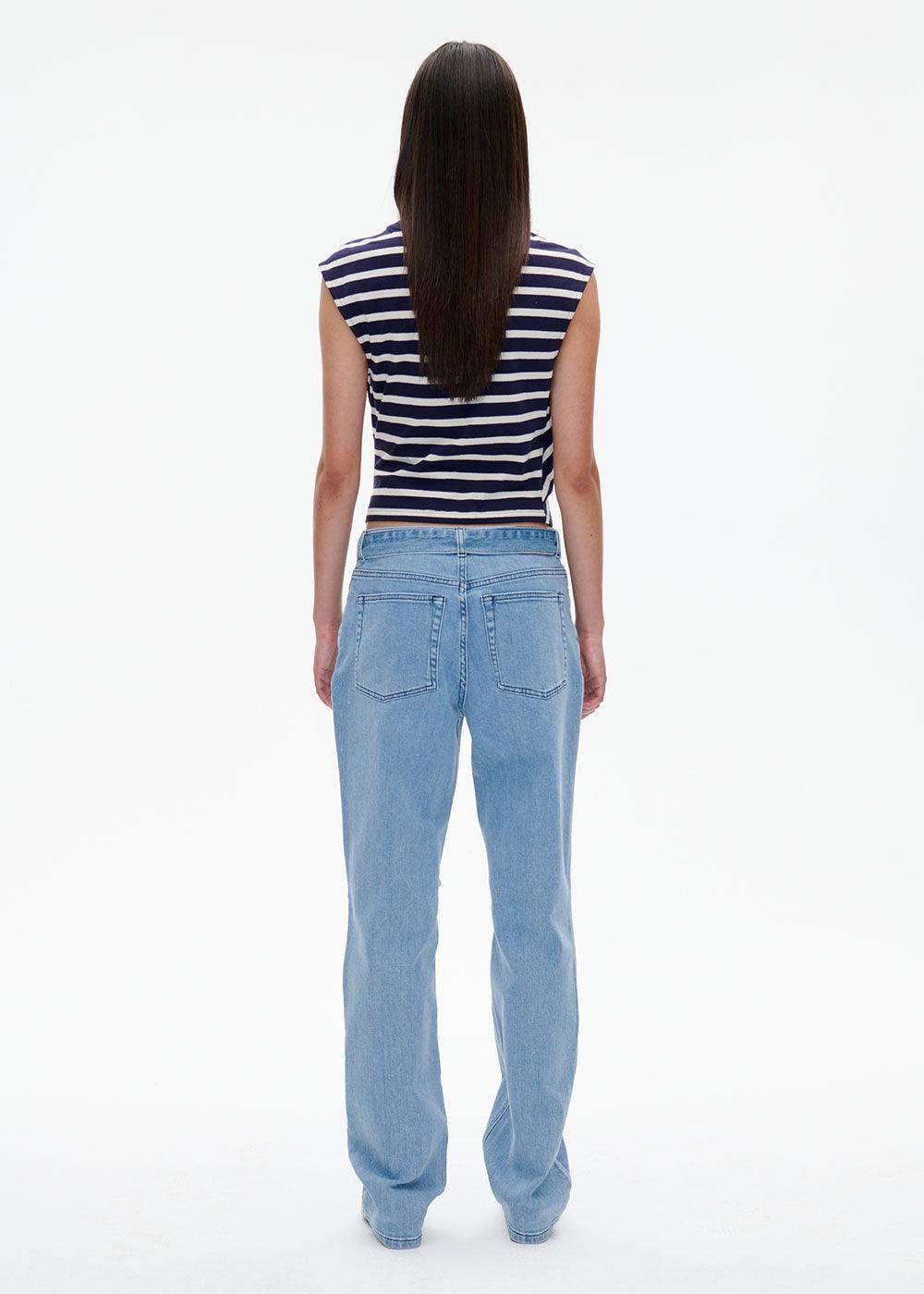 Woman in a navy striped sleeveless crop top and light blue straight-leg jeans, rear view