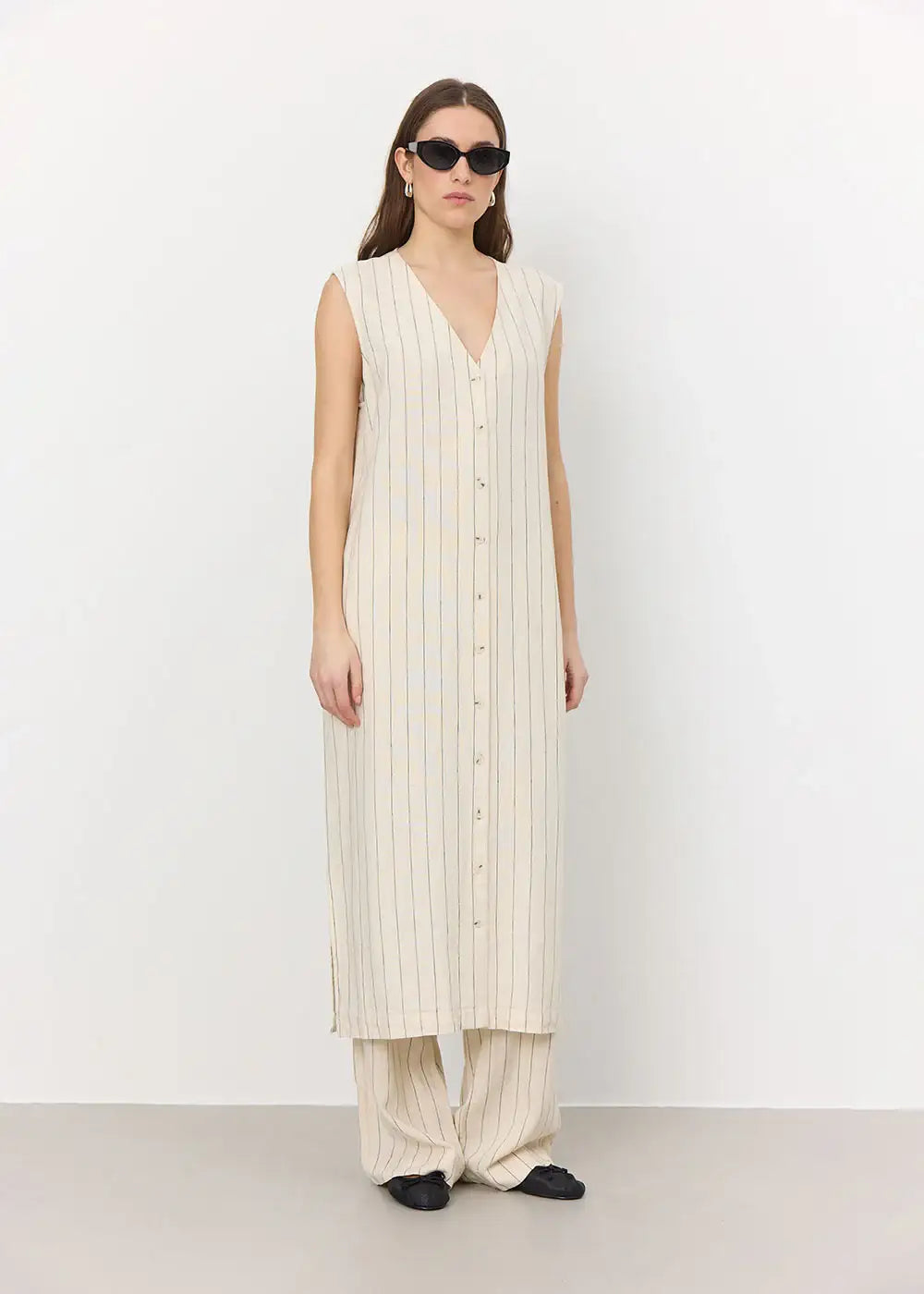 Woman wearing sleeveless striped button-front long vest and matching wide-leg pants.