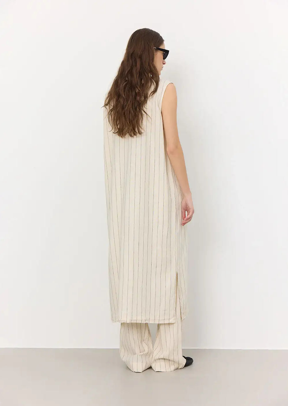 Woman in cream sleeveless pinstripe long tunic and matching wide-leg pants, rear view