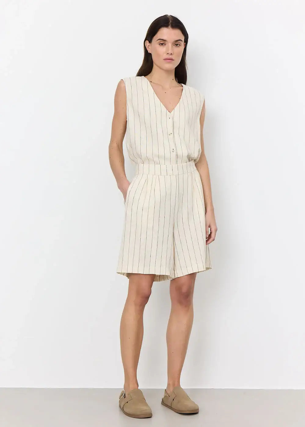 Woman wearing sleeveless cream striped button top and matching high-waisted shorts