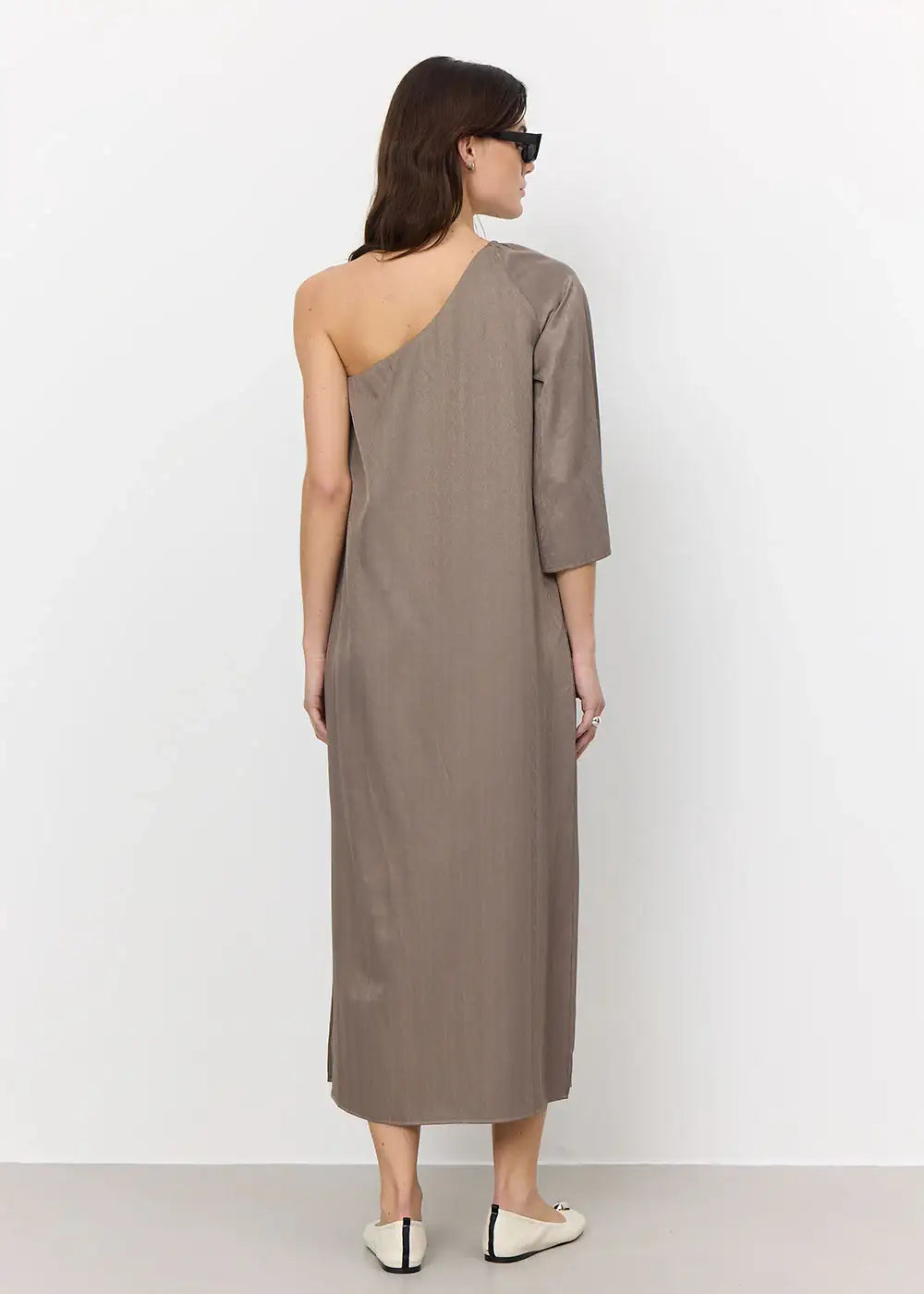 Woman wearing taupe one-shoulder midi dress with single sleeve, back view