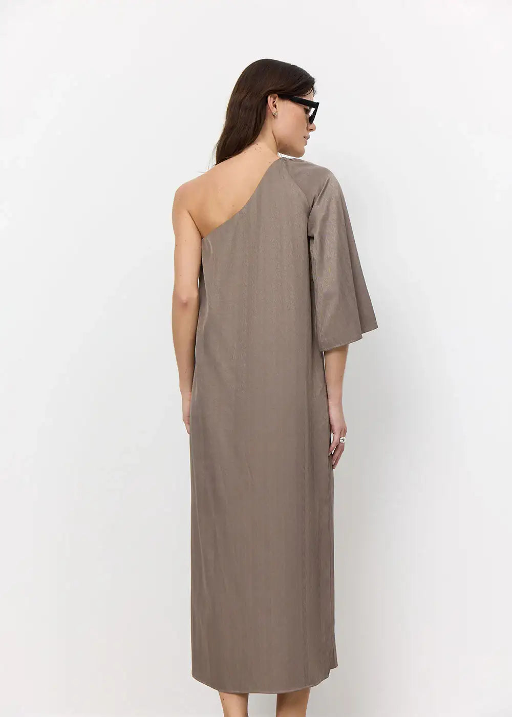 Woman wearing taupe one-shoulder midi dress with single sleeve, back view