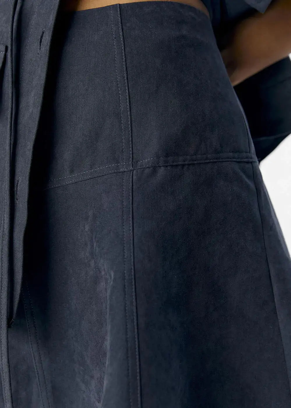 Close-up of dark denim skirt with visible seam details and high-waisted fit