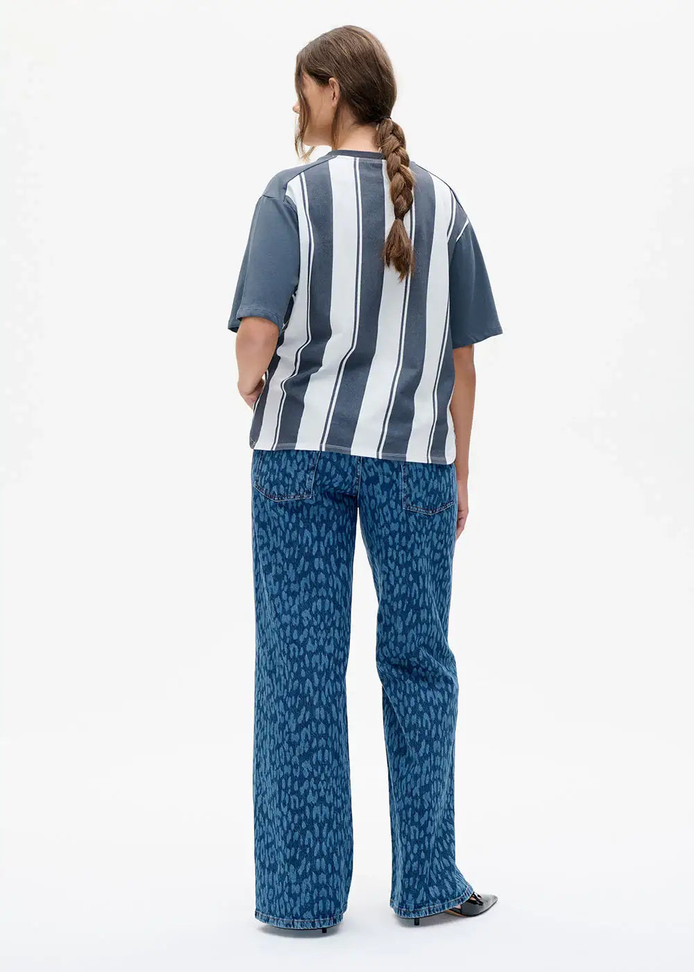 Woman wearing a striped short sleeve top and blue animal print wide leg jeans, back view