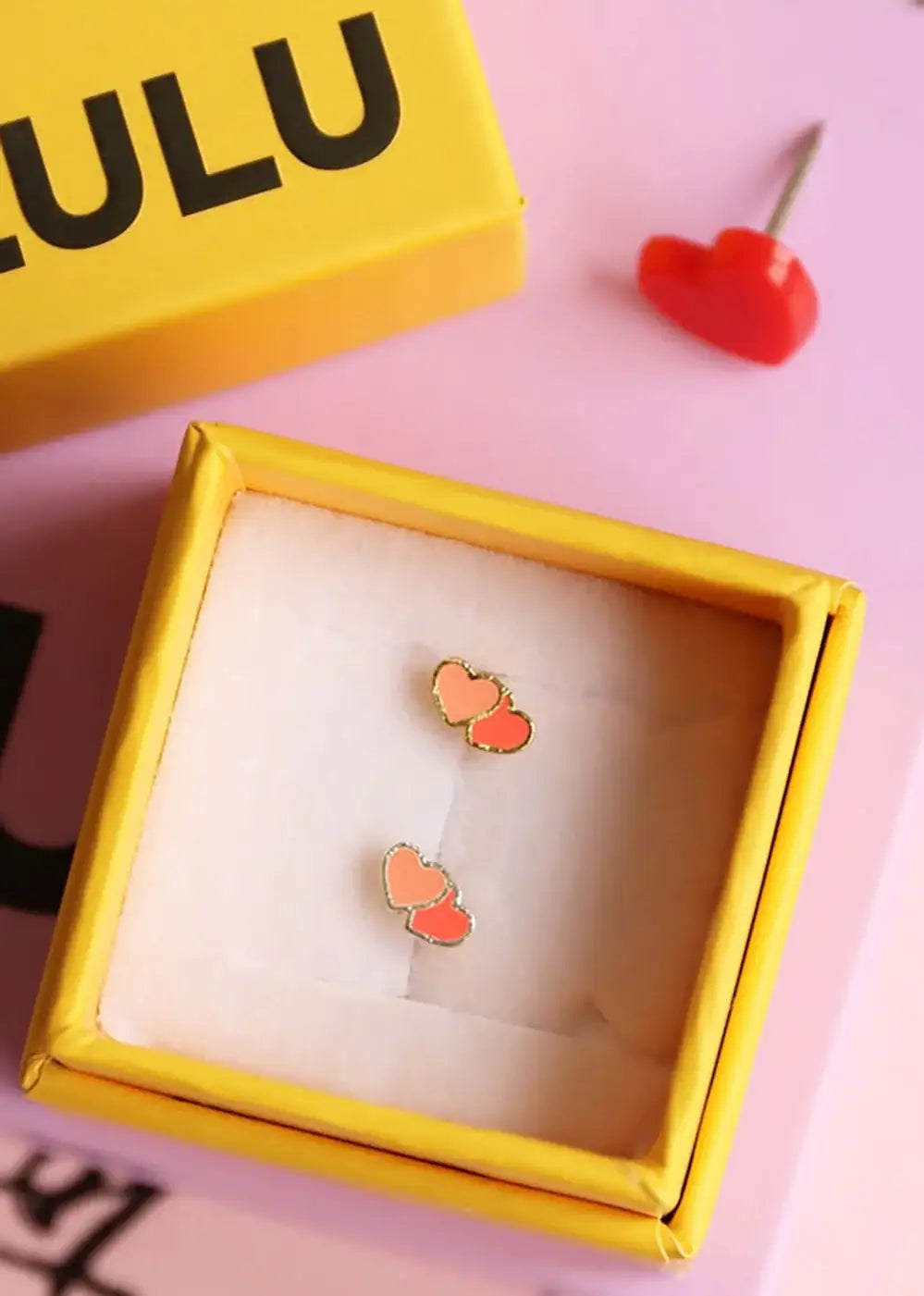 Gold-plated double heart stud earrings in coral and orange, presented in a yellow gift box