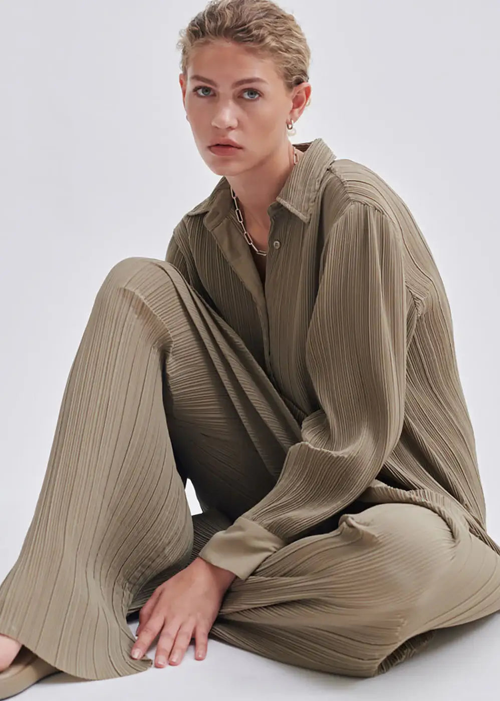 Woman in beige pleated shirt and wide-leg trousers, minimalist fashion style