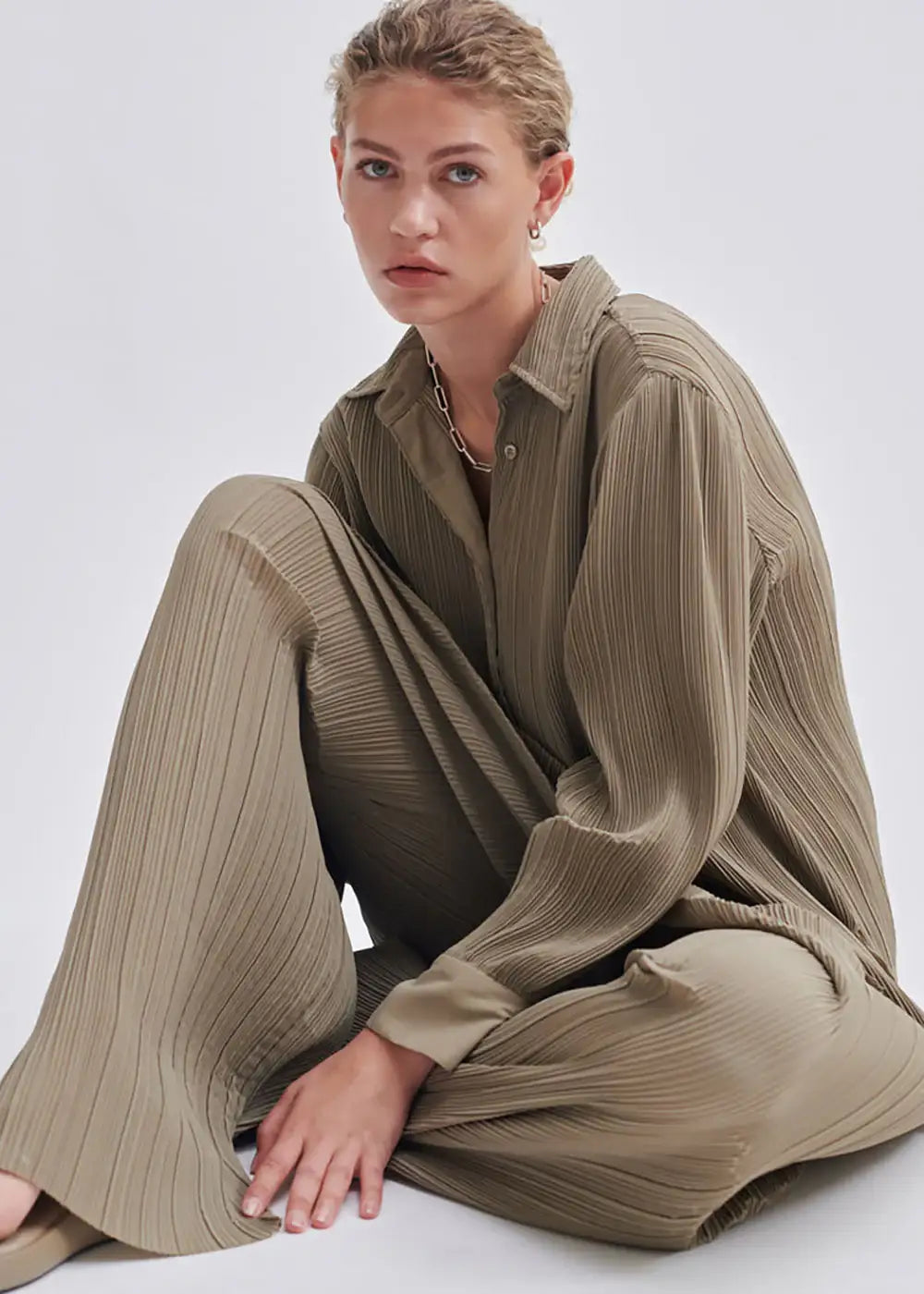 Woman in beige pleated shirt and wide-leg trousers, minimalist fashion style