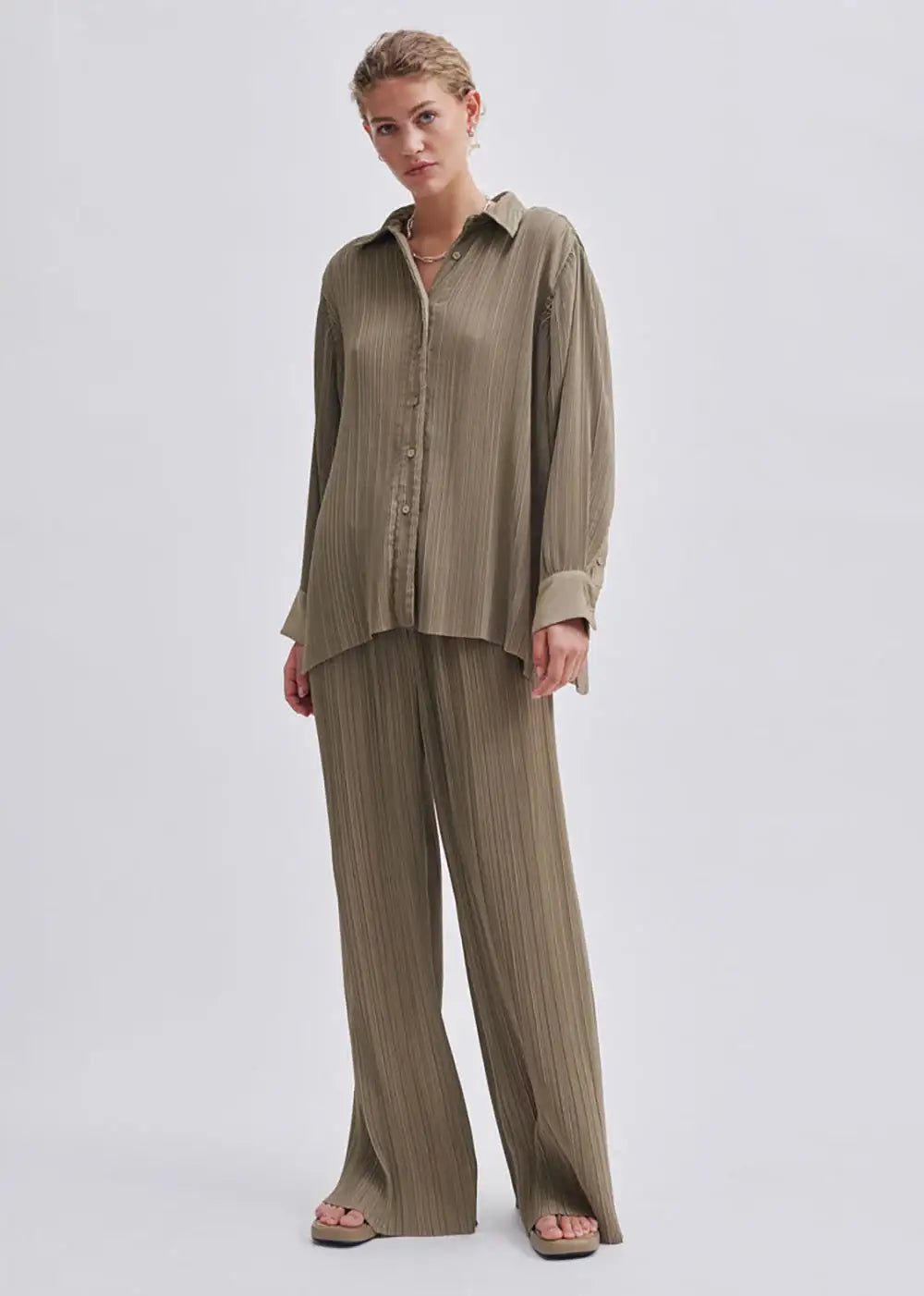 Woman wearing relaxed fit khaki pleated shirt and wide-leg trousers set
