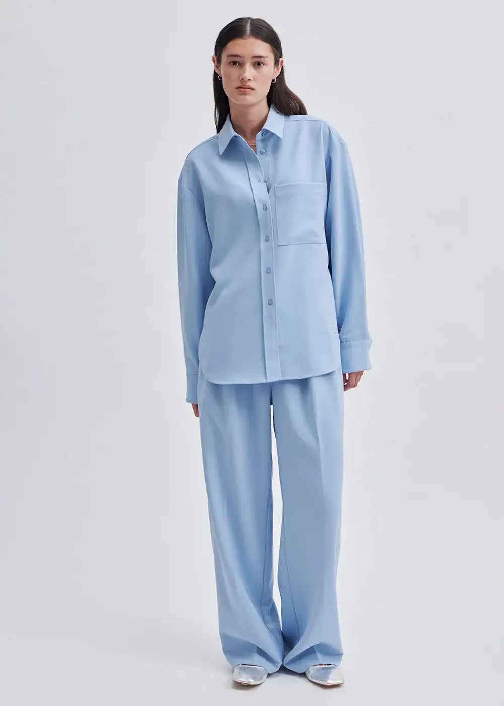 Woman wearing relaxed light blue button-up shirt and matching wide-leg trousers