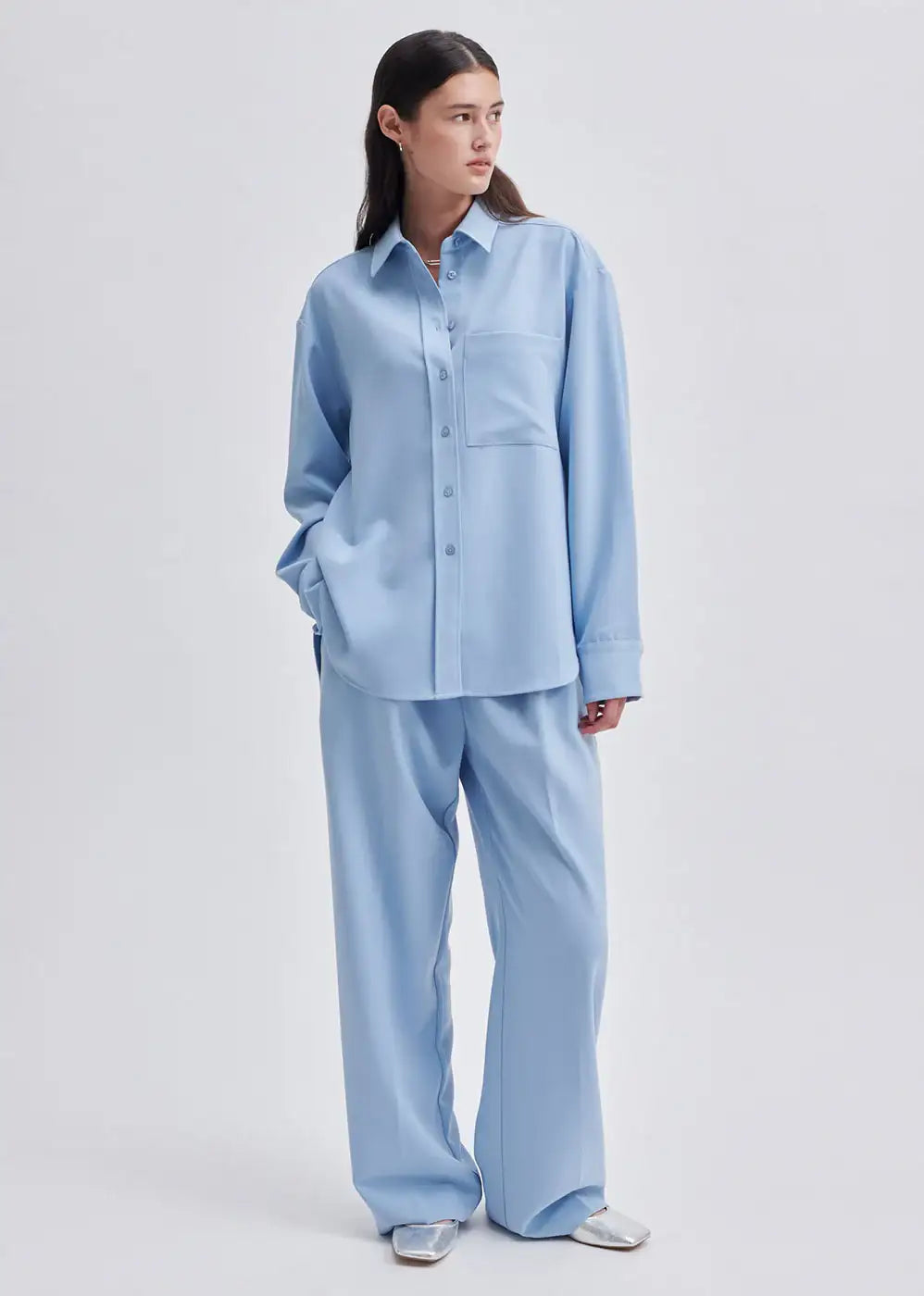 Woman wearing light blue oversized shirt and wide leg trousers, minimalist fashion outfit
