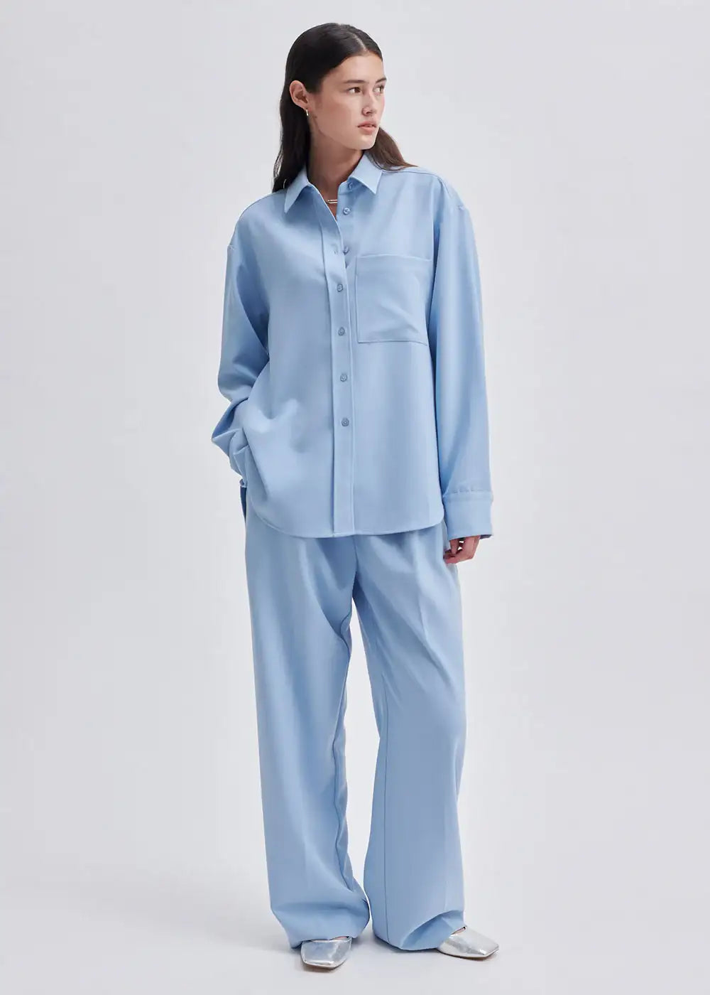 Woman wearing light blue oversized shirt and wide leg trousers, minimalist fashion outfit