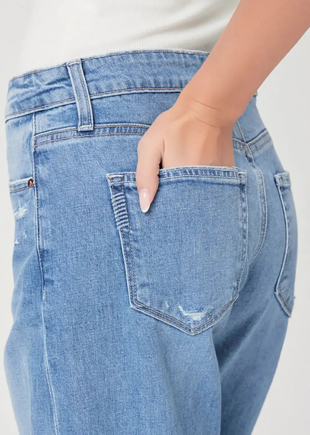 Close-up of light blue high-waisted jeans with hand in back pocket and subtle distressing