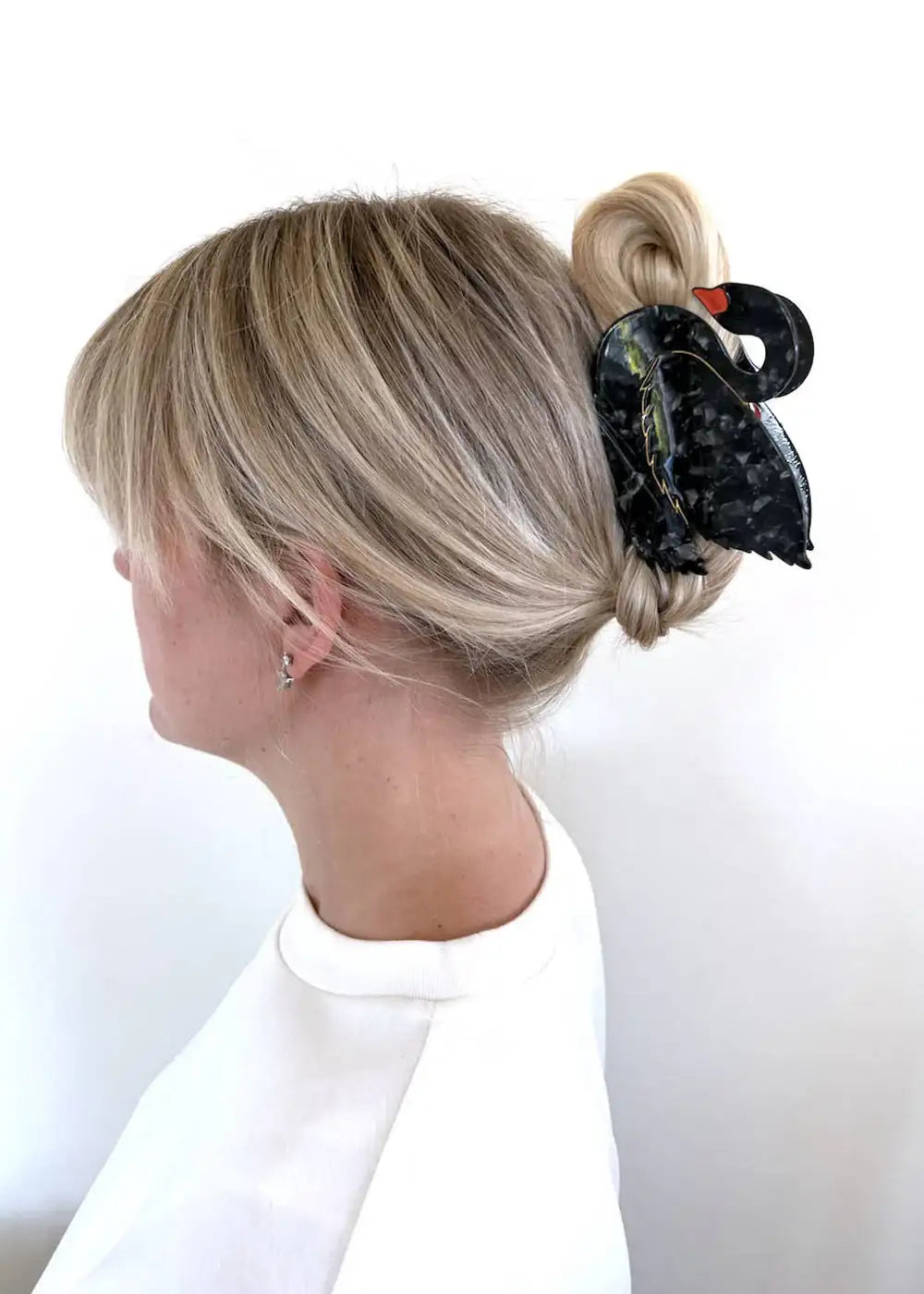 Woman with blonde hair styled in a bun wearing a black swan hair clip accessory