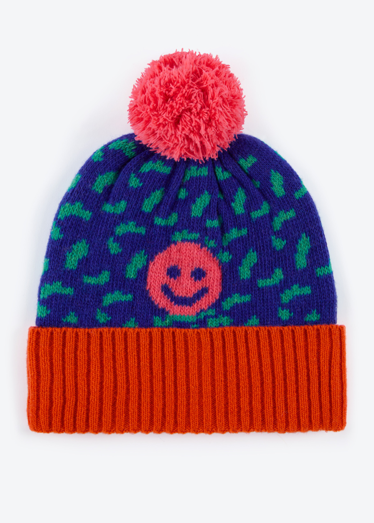 Colorful knit beanie with smiley face design and red pom-pom on a white background