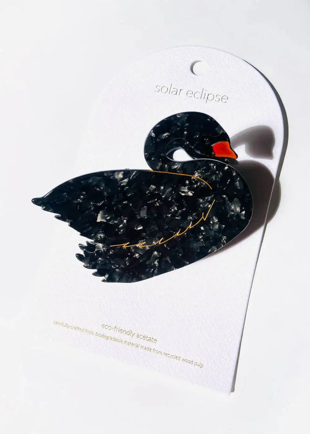 Eco-friendly acetate black swan brooch with marbled texture and orange beak on white card