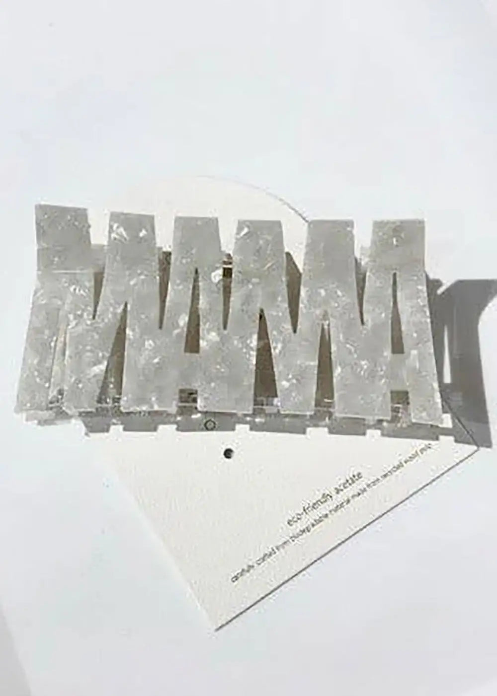 Pearlescent acrylic hair clip spelling MAMA, set on a white background, fashion accessory