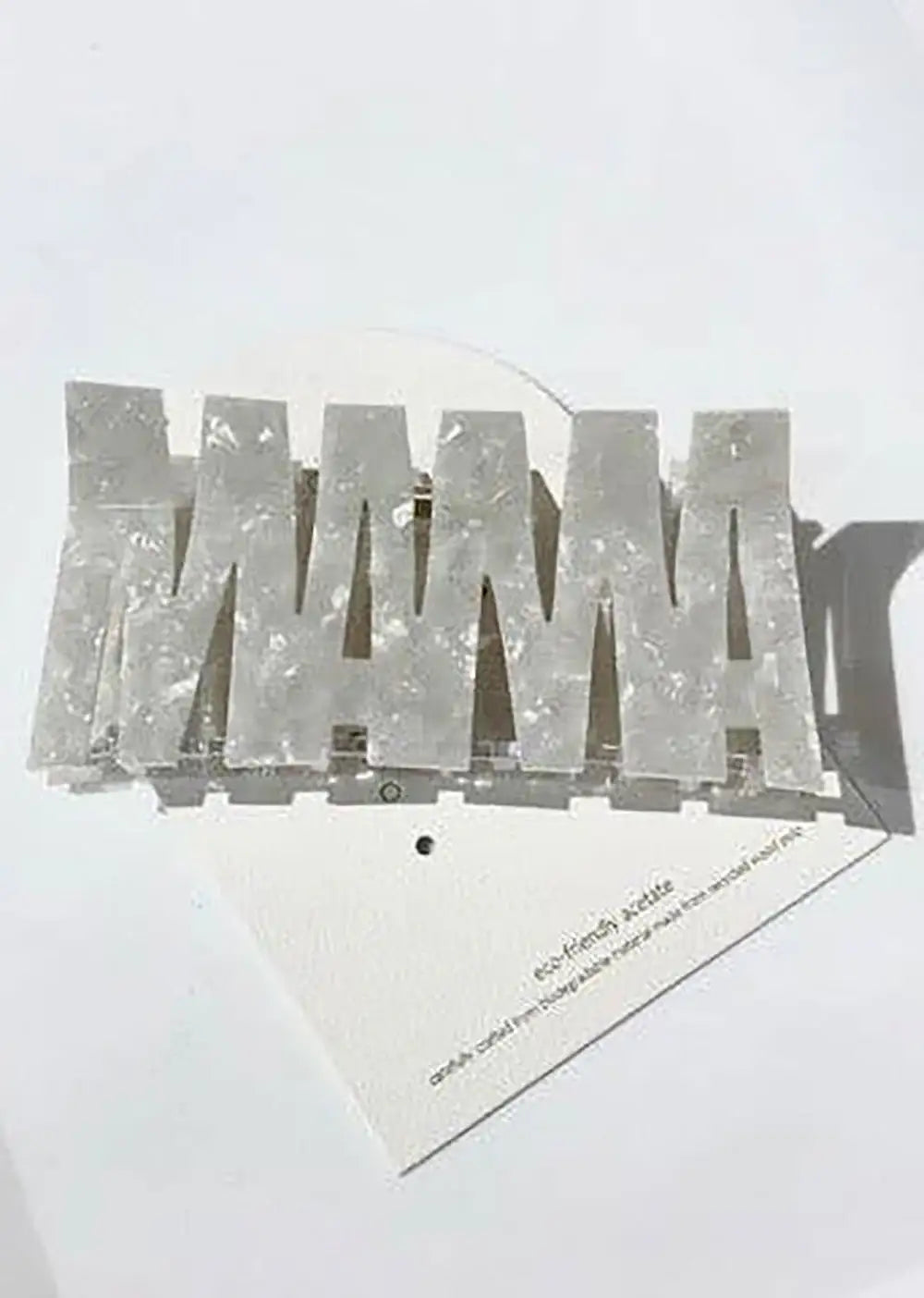 Pearlescent acrylic hair clip spelling MAMA, set on a white background, fashion accessory