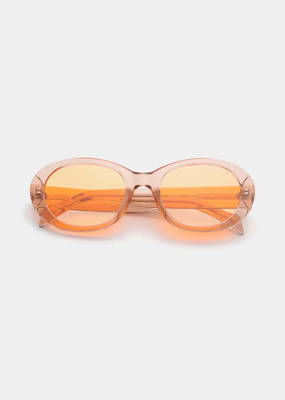 Oval champagne sunglasses with translucent orange lenses on a white background