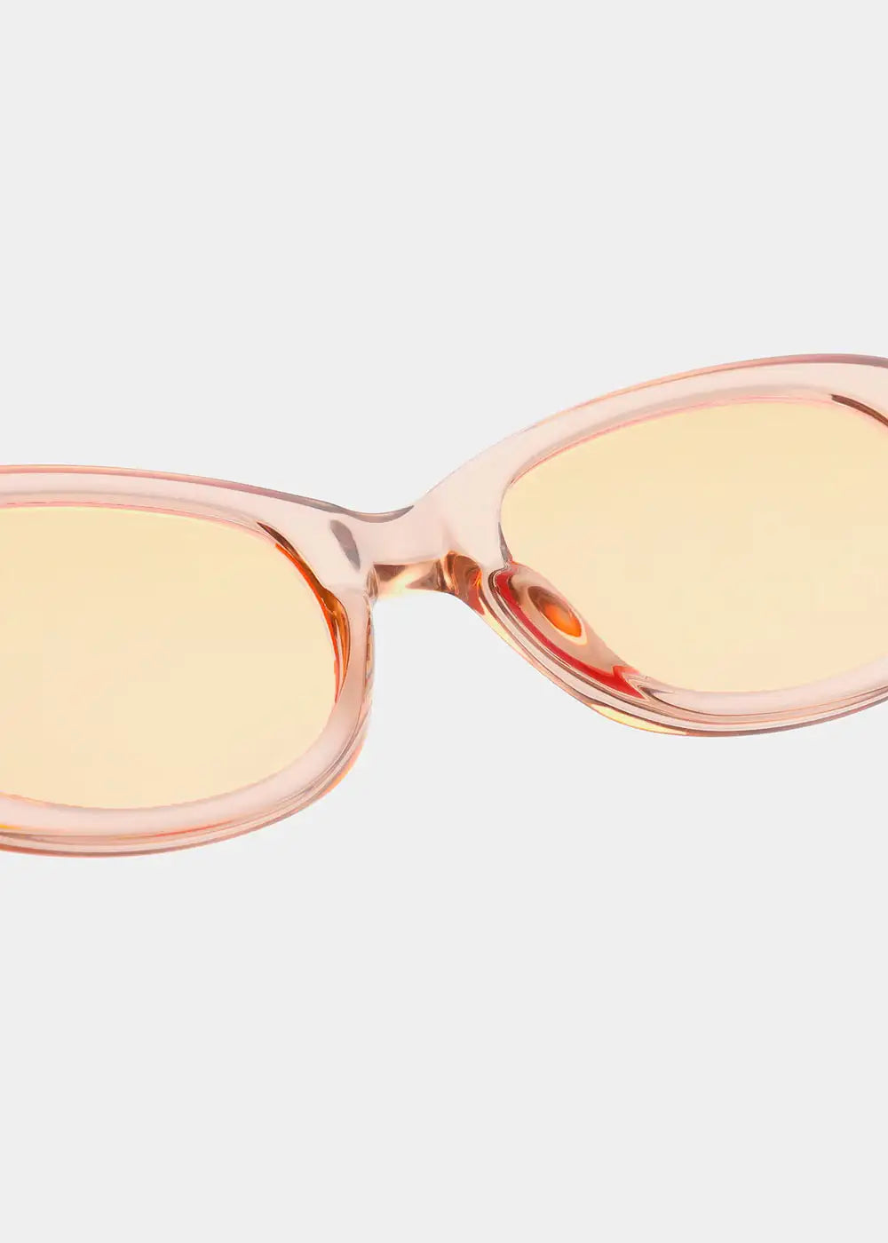 Close-up of stylish champagne-colored sunglasses with translucent pink frames and tinted lenses