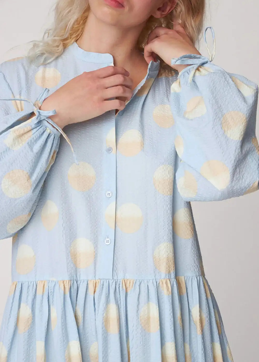 Light blue maxi dress with large beige polka dots and textured fabric, shown on model