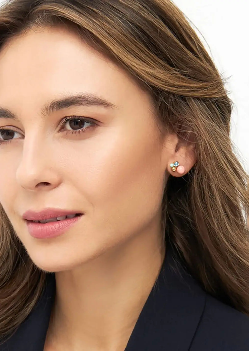 Woman wearing gold plated floral stud earring with coral and blue accents