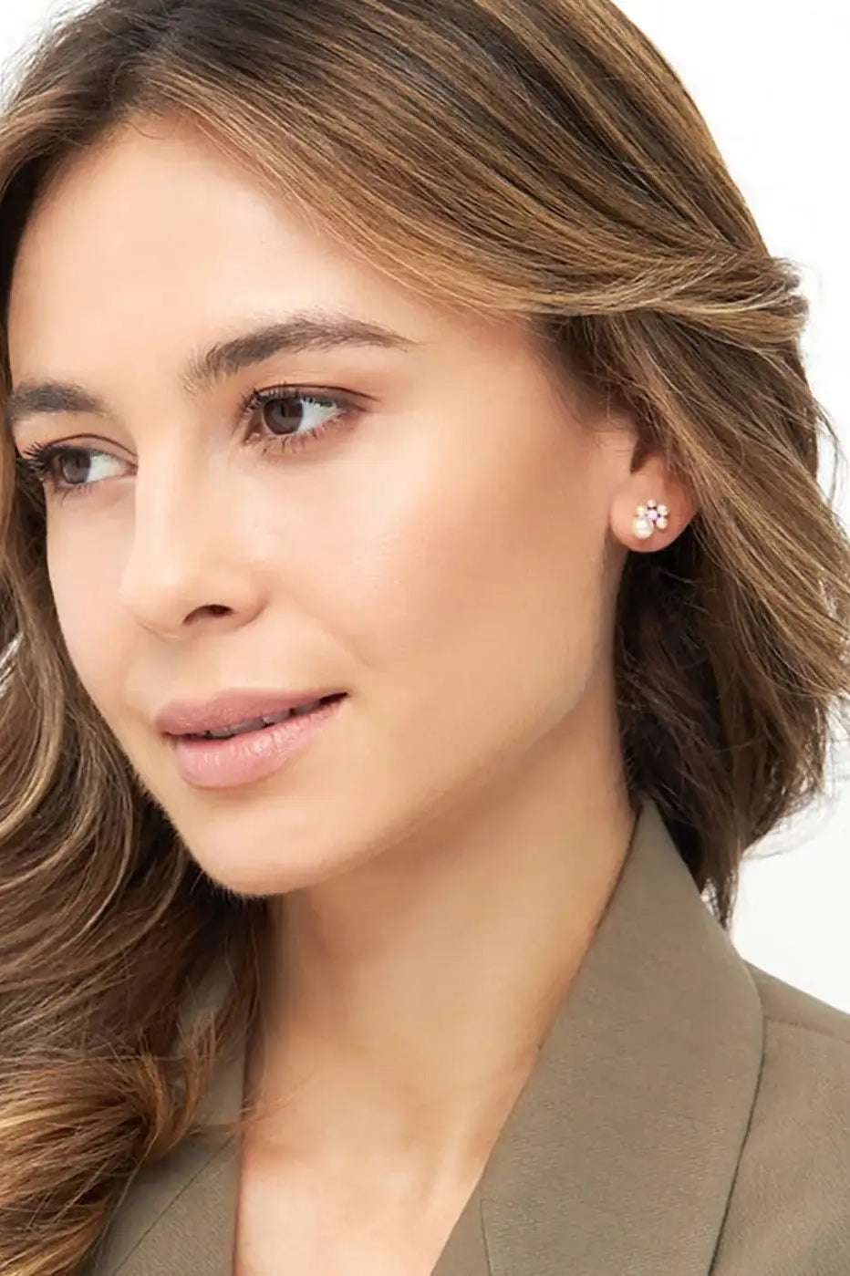 Woman wearing gold-plated floral stud earring with pearl accents, close-up