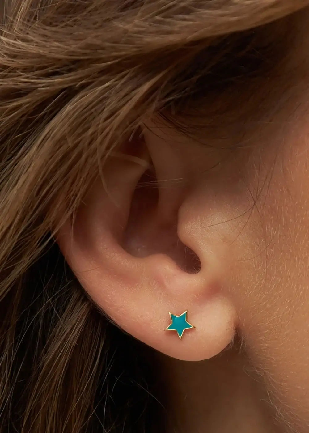 Petrol blue star-shaped gold plated ear stud on pierced ear