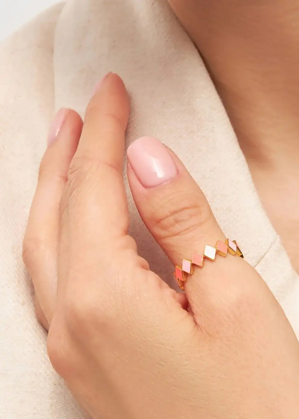 Gold plated geometric pink enamel ring on hand with light pink manicure