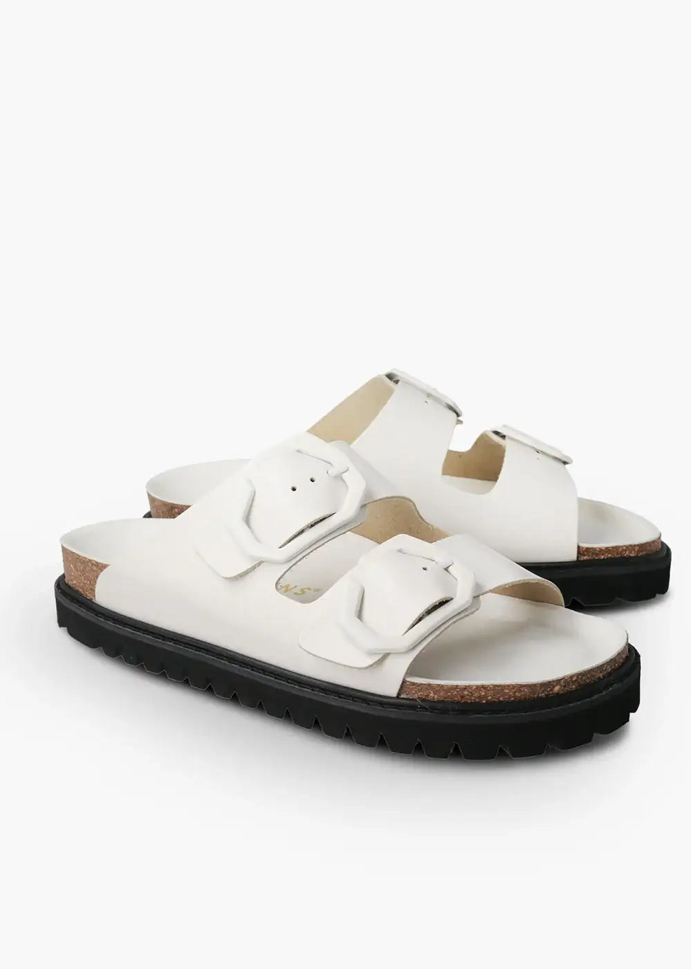 White double buckle sandals with cork footbed and black chunky sole on white background