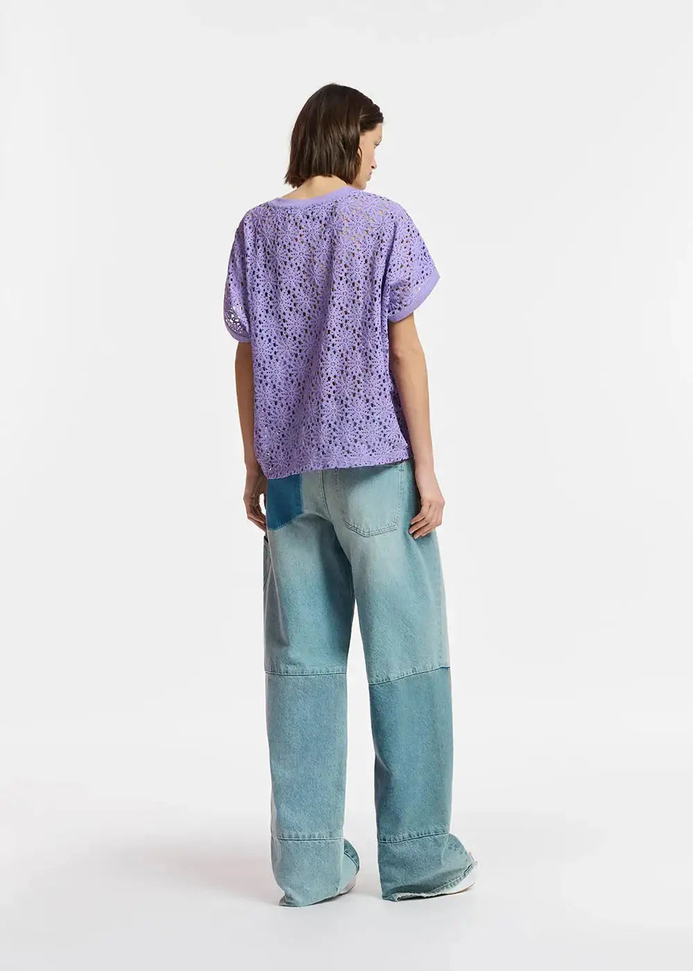 Woman wearing a purple crochet top and loose patchwork wide-leg jeans, back view