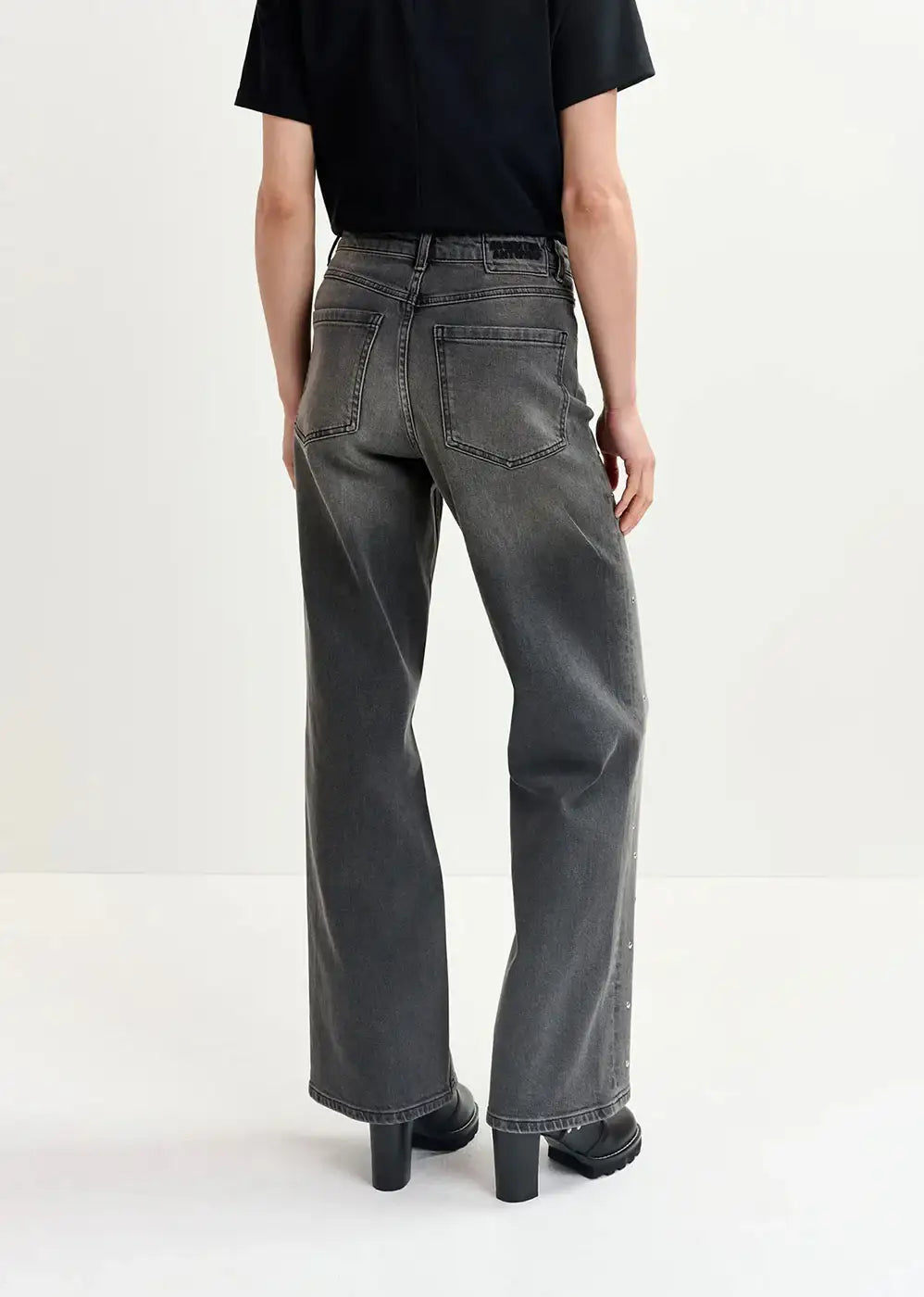 Back view of person wearing loose fit washed black jeans and black boots