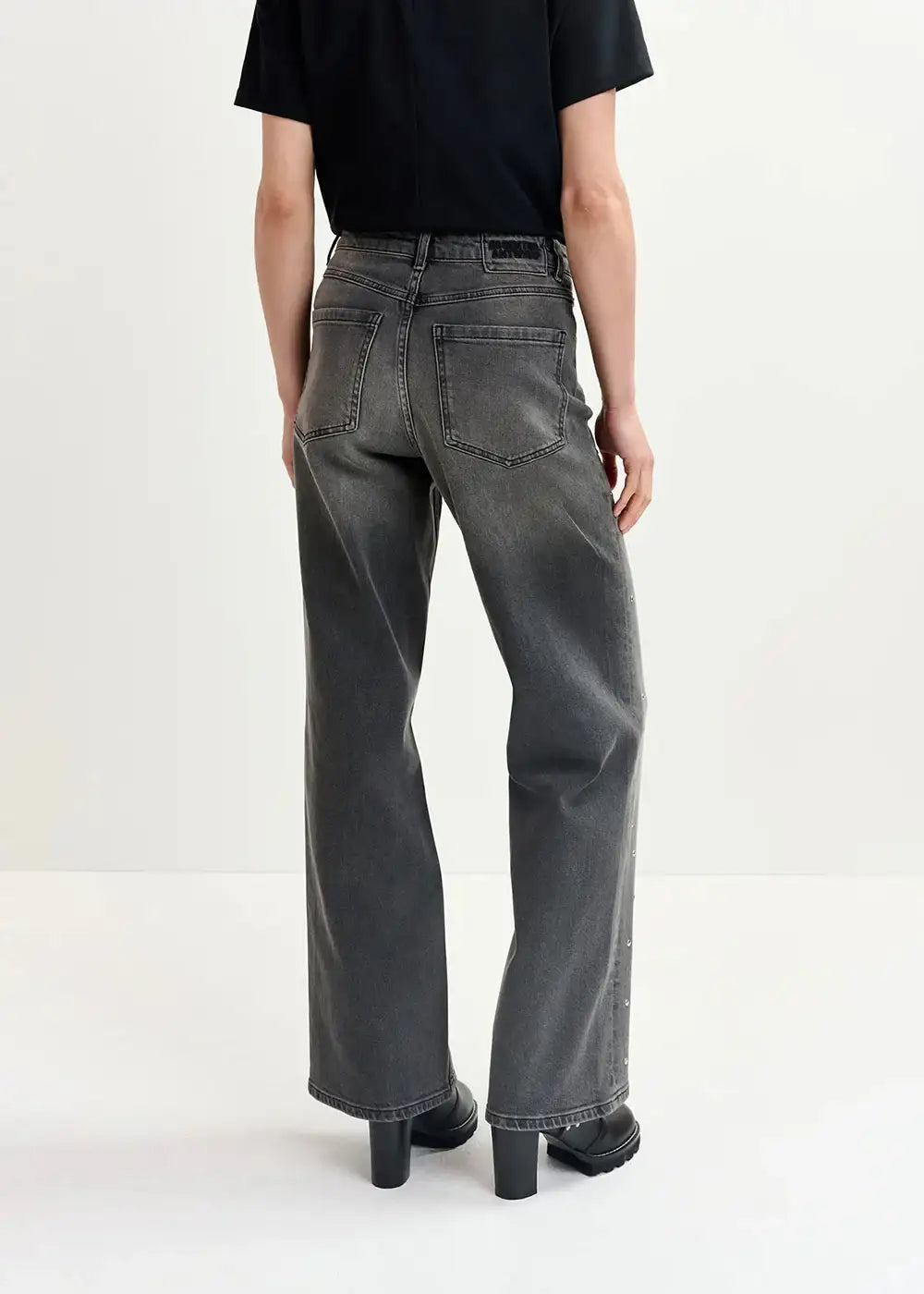 Back view of person wearing loose fit washed black jeans and black boots