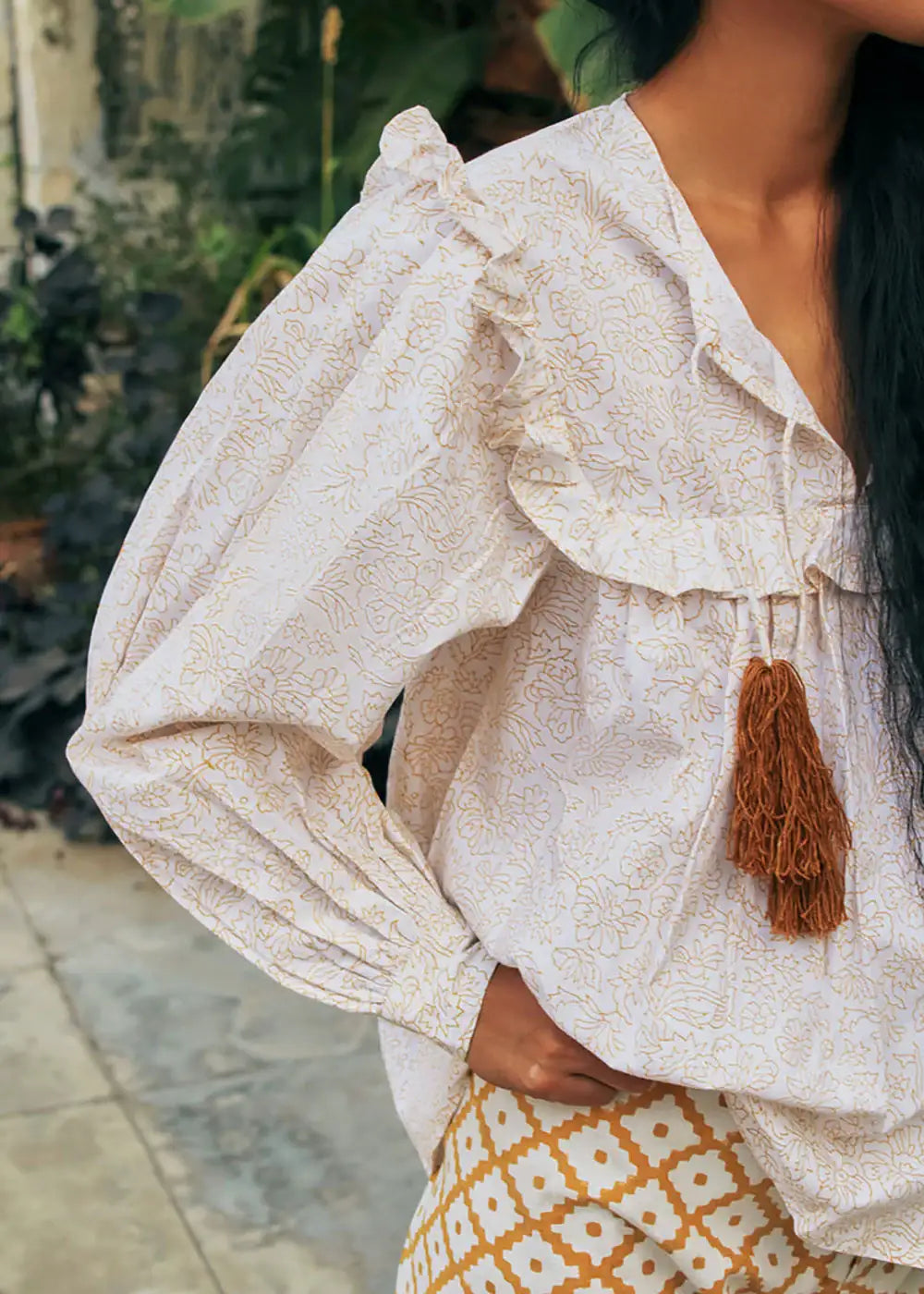 Woman wearing a floral ruffle blouse with tassel tie and geometric print trousers