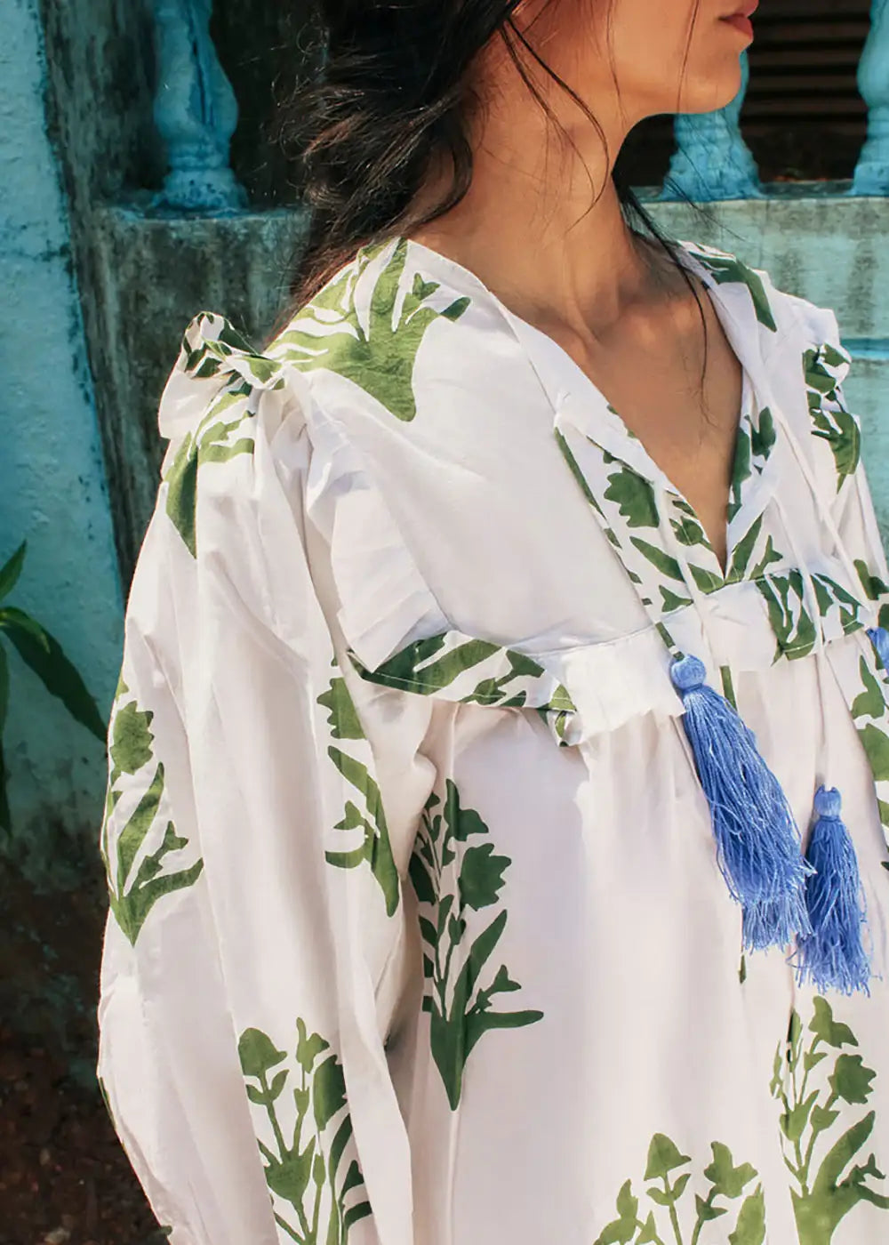 White boho blouse with green leaf print and blue tassel ties, worn outdoors