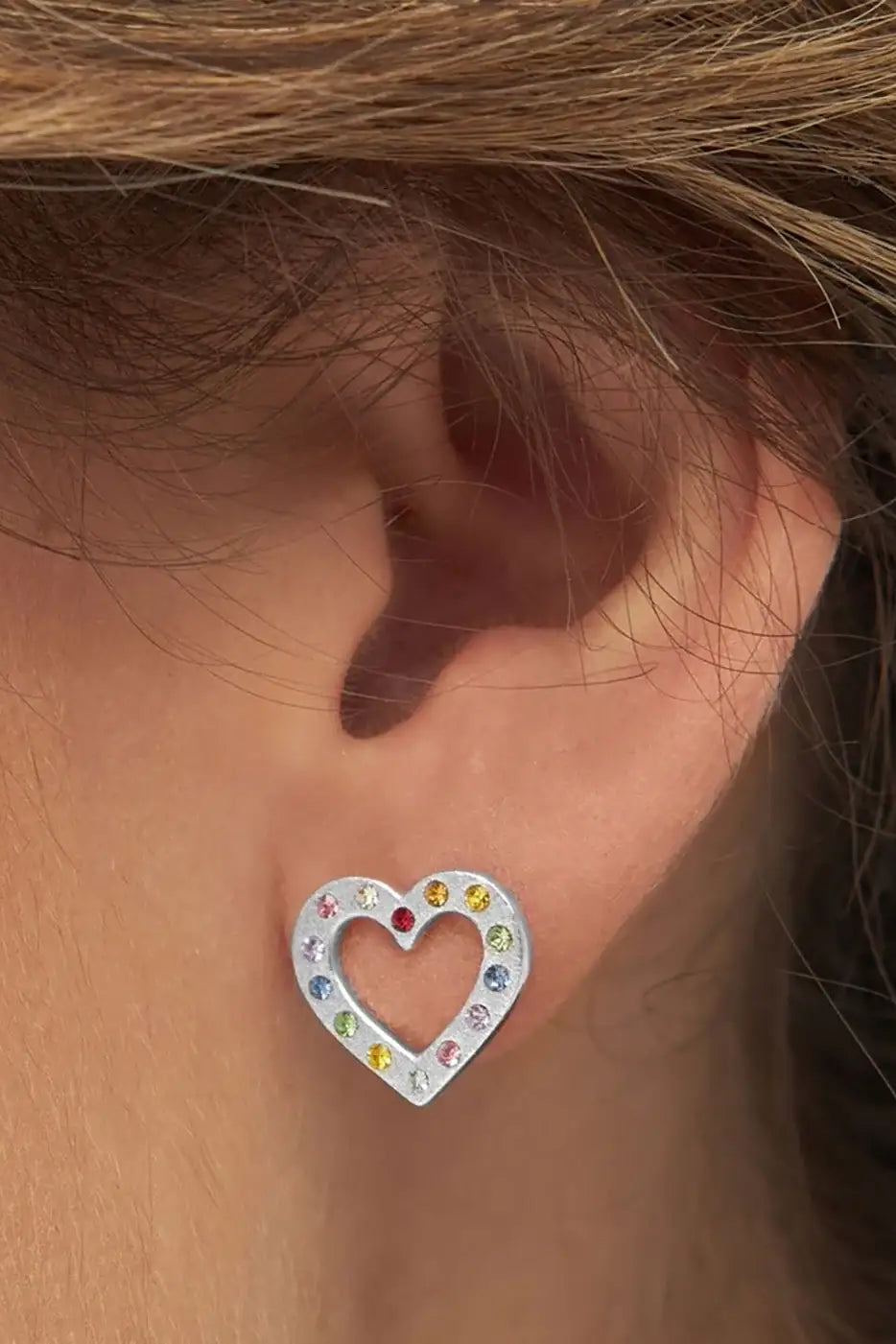 Silver heart-shaped ear stud with multicolour gemstones worn on ear
