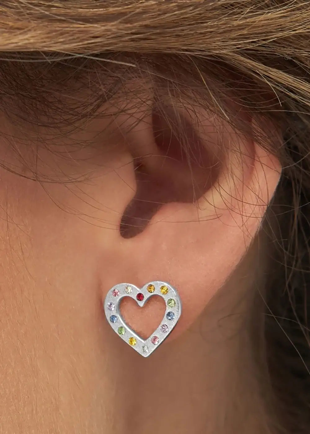 Silver heart-shaped ear stud with multicolour gemstones worn on ear