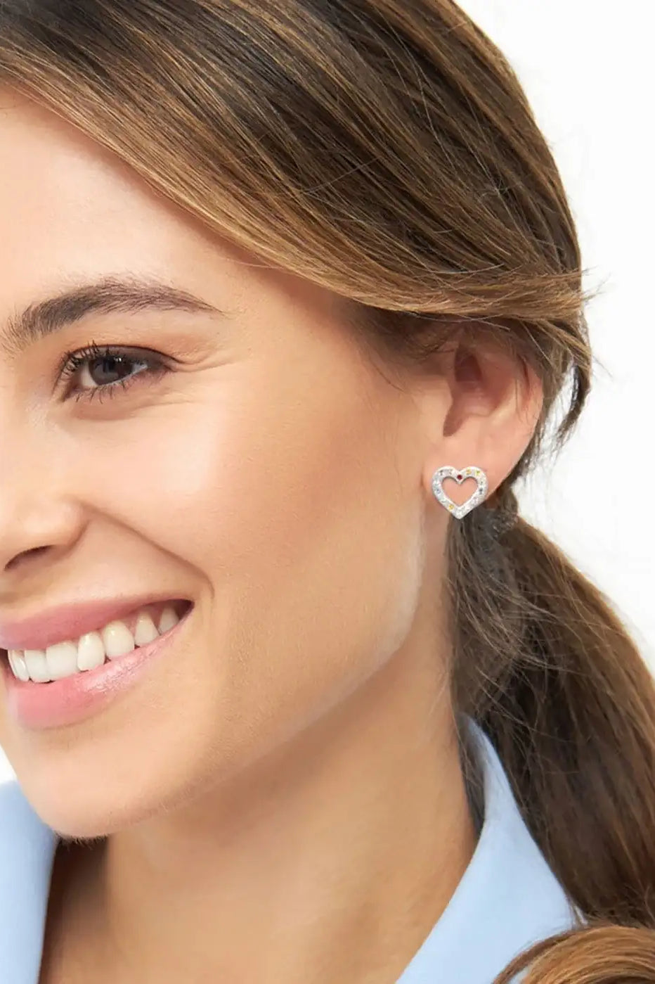 Woman wearing a silver heart-shaped rainbow crystal stud earring