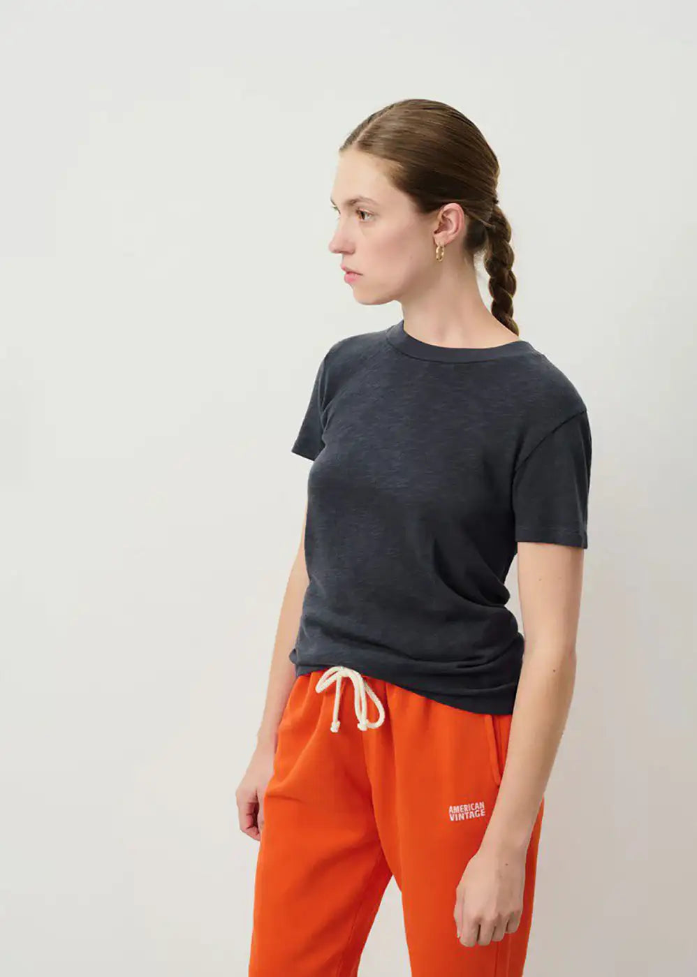 Woman modeling casual outfit with dark short sleeve t-shirt and orange American Vintage joggers