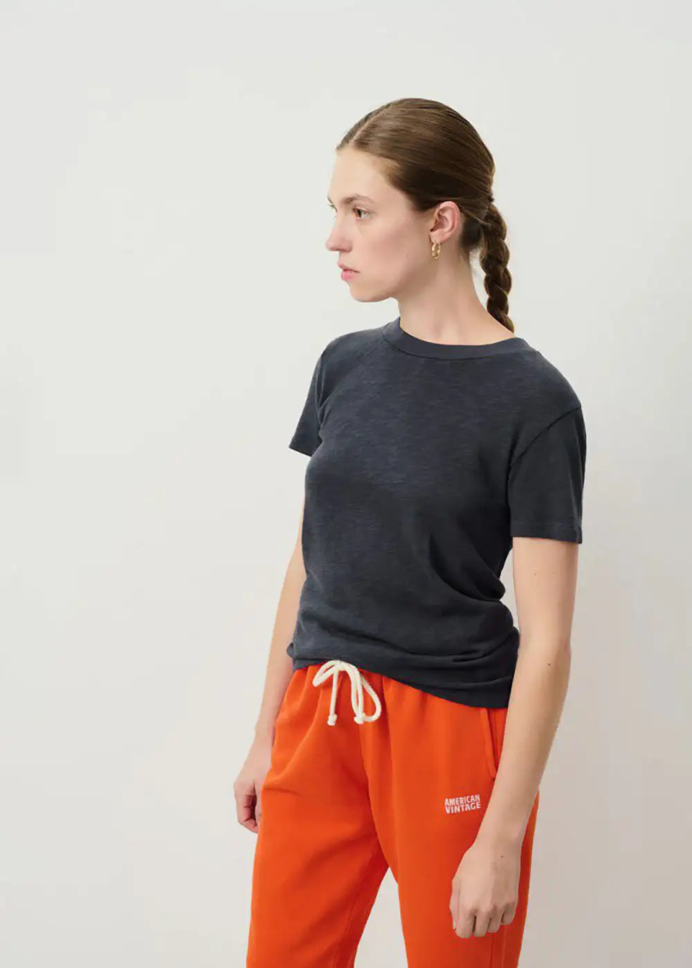 Woman modeling casual outfit with dark short sleeve t-shirt and orange American Vintage joggers