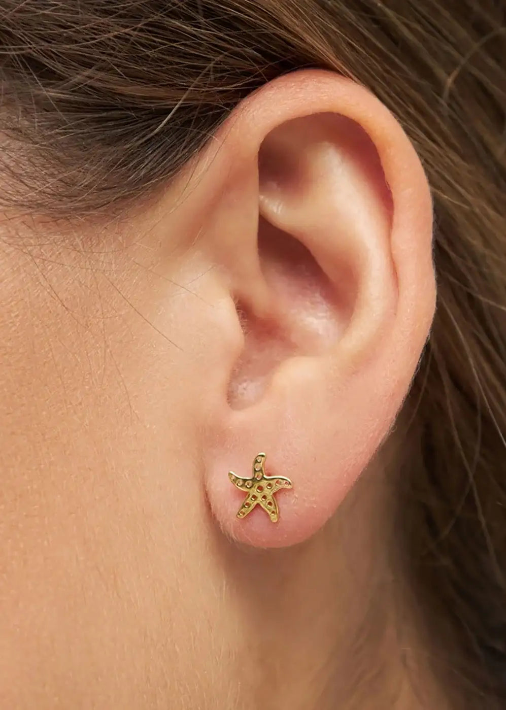 Gold plated starfish stud earring on ear, delicate nautical jewelry accessory