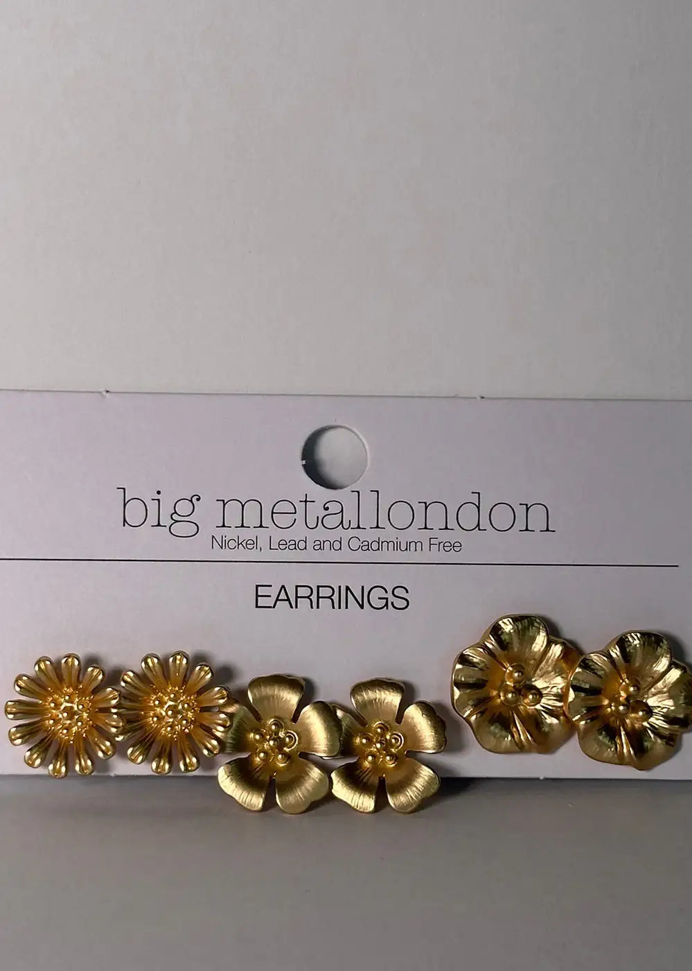 Set of three pairs gold-tone floral stud earrings on white card, nickel free