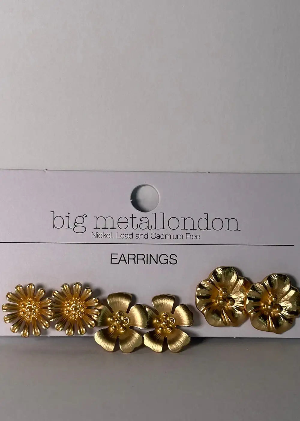 Set of three pairs gold-tone floral stud earrings on white card, nickel free