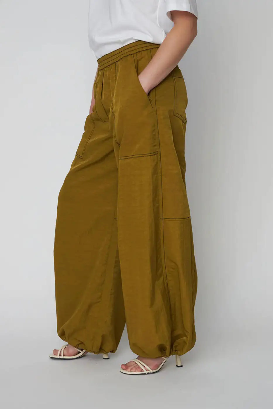 Woman wearing olive green oversized wide-leg workwear pants with elastic cuffs and pockets