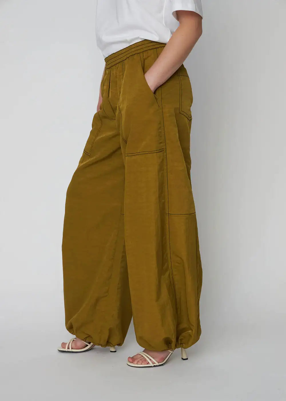 Woman wearing olive green oversized wide-leg workwear pants with elastic cuffs and pockets