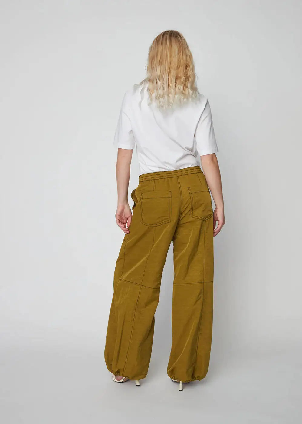 Back view of woman wearing olive oversized workwear pants with elastic waist and pockets