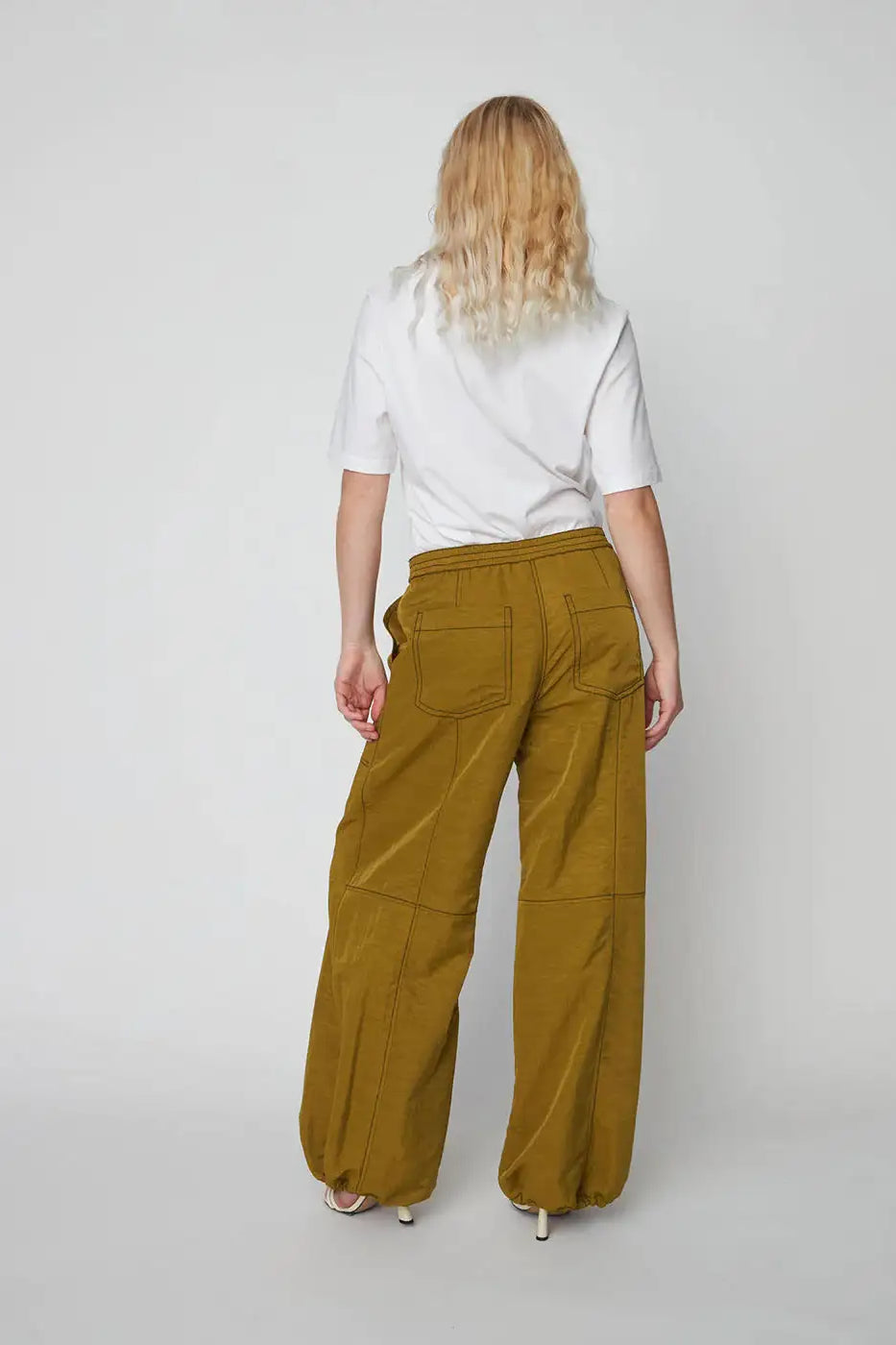 Back view of woman wearing olive oversized workwear pants with elastic waist and pockets