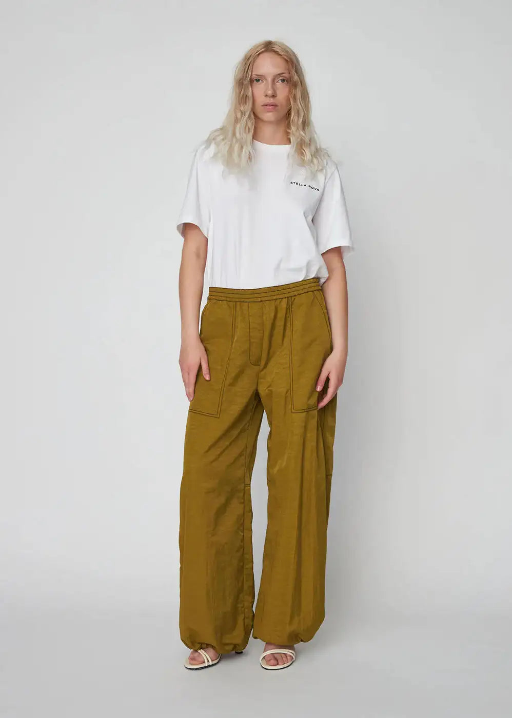 Woman wearing olive green oversized workwear pants with front pockets and a white t-shirt