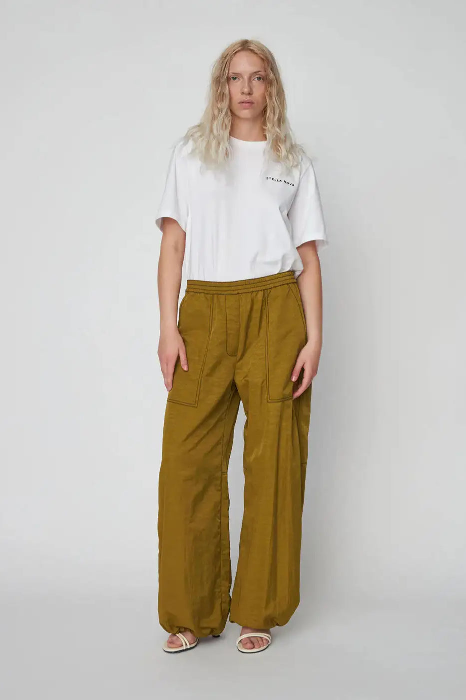 Woman wearing olive green oversized workwear pants with front pockets and a white t-shirt