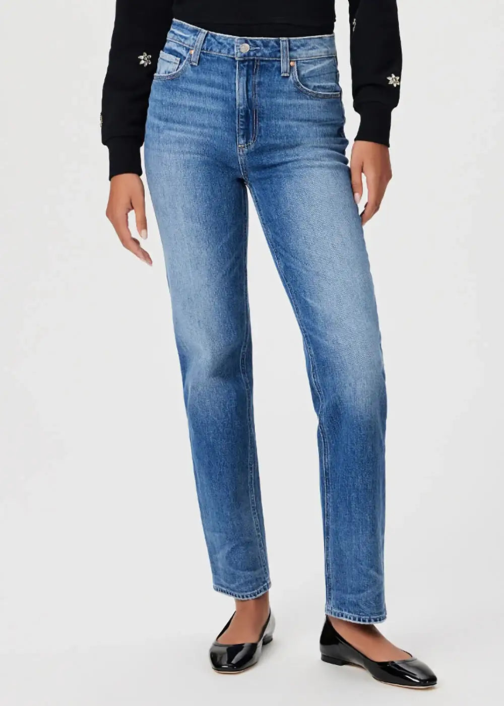 Woman wearing high rise straight leg blue jeans and black flats on white background